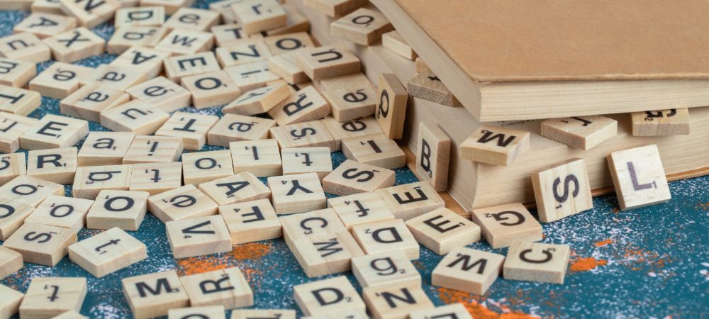 Wooden dice with letters on them between the pages of a book. High quality photo