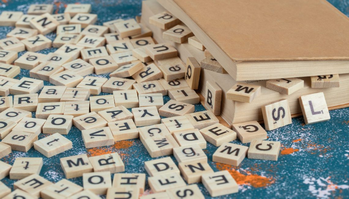 Wooden dice with letters on them between the pages of a book. High quality photo