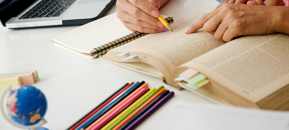 Education concept. Students studying and brainstorming campus concept. Close up of students discussing their subject on books textbooks and writing to notebook. Seclective focus.