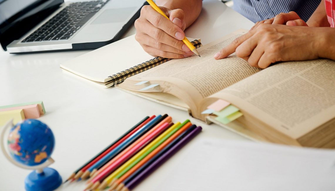Education concept. Students studying and brainstorming campus concept. Close up of students discussing their subject on books textbooks and writing to notebook. Seclective focus.